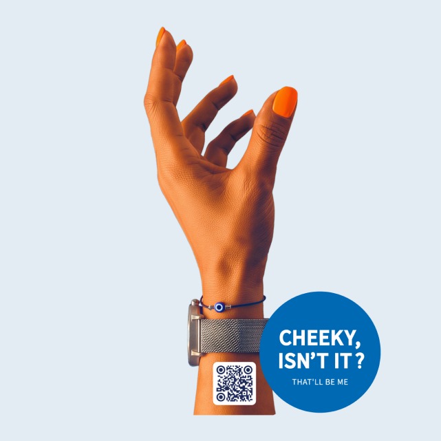 A hand with an orange nail wearing the 'Cheeky, isn't it?' QR sticker